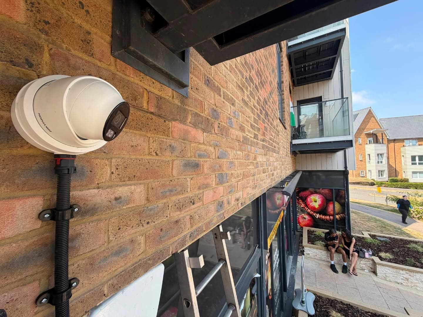 HIKVISION dome CCTV camera installed on the brick exterior of an apartment building