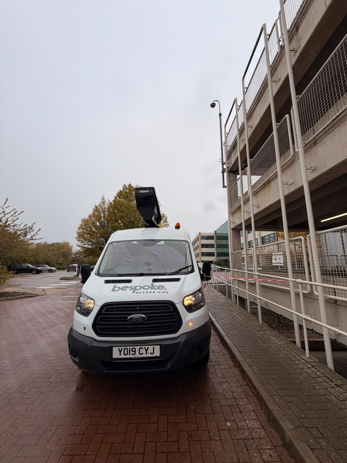 Front of the Bespoke Access Hire van, taped off beside the multi-storey car park, below a pole-mounted CCTV camera