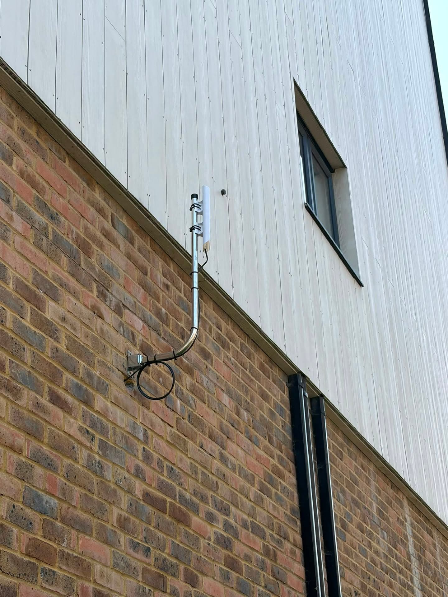Wireless CCTV link antenna and conduit run mounted high on a clad apartment building