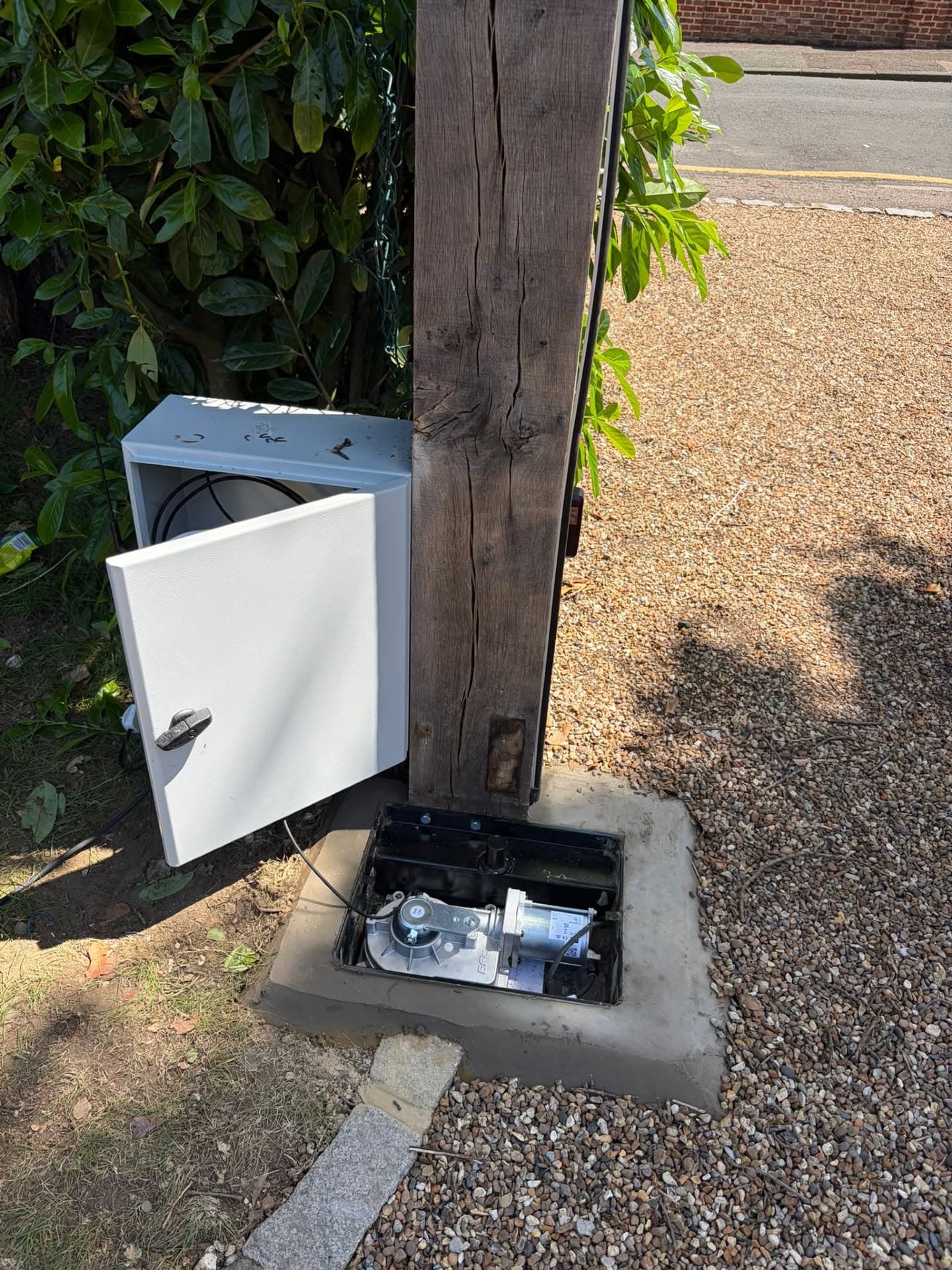 Underground gate motor installed at the foot of an oak gate post