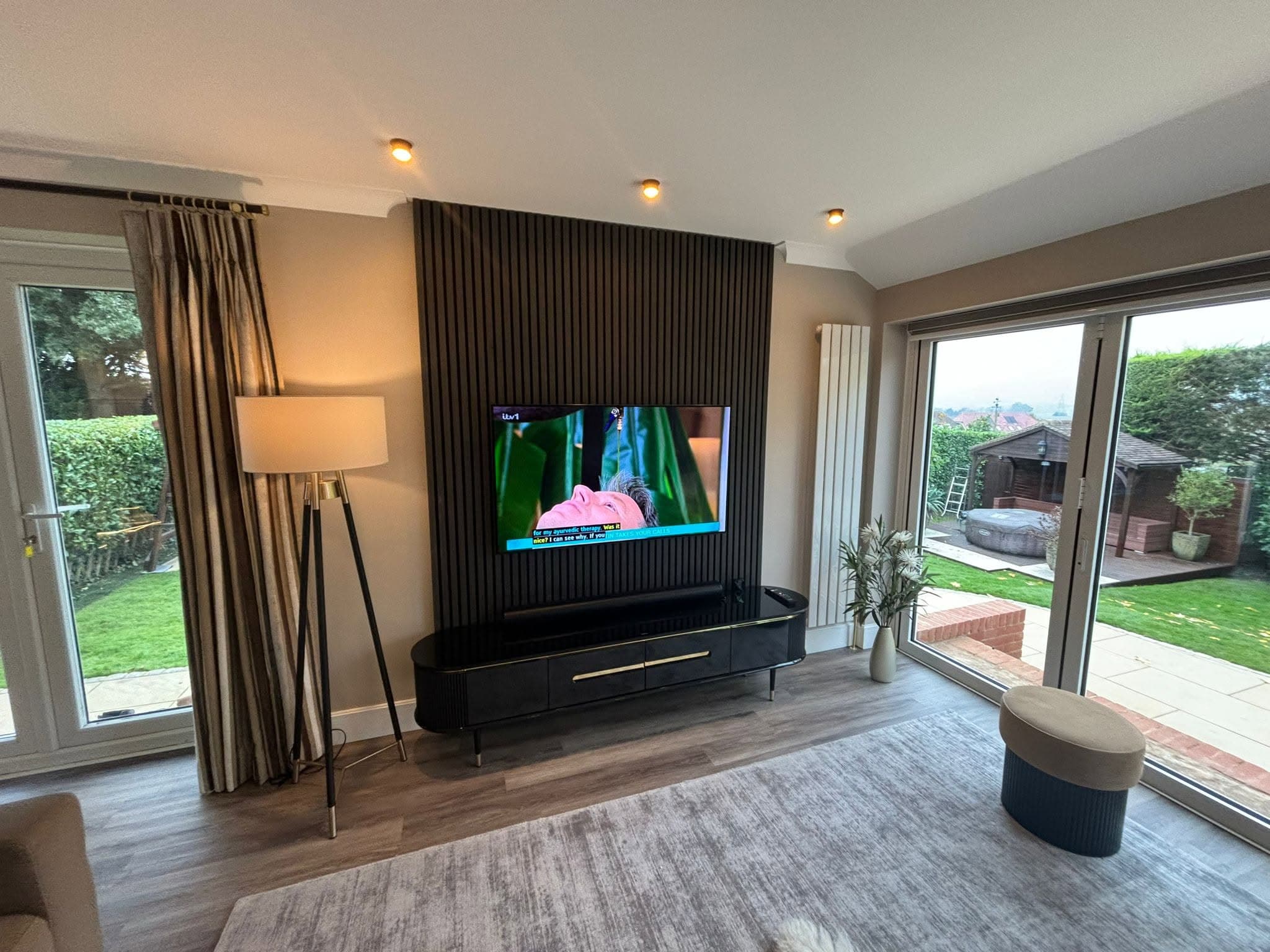 Dark slatted media wall with wall-mounted TV in an open-plan living room