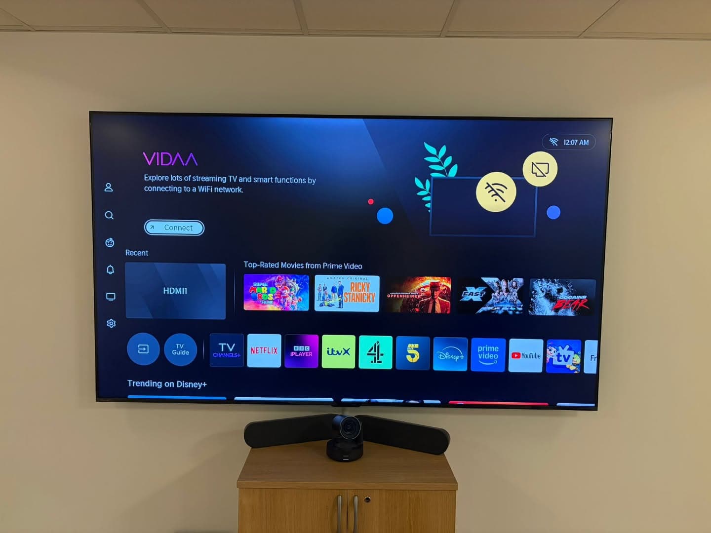 Wall-mounted smart TV and video-conferencing camera set up in an office meeting room