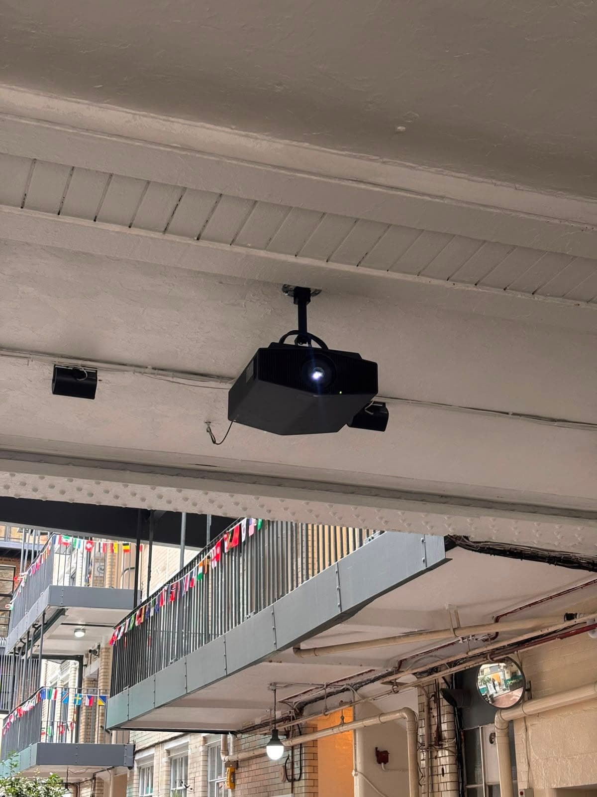 Ceiling-mounted projector and speaker installation under a covered walkway
